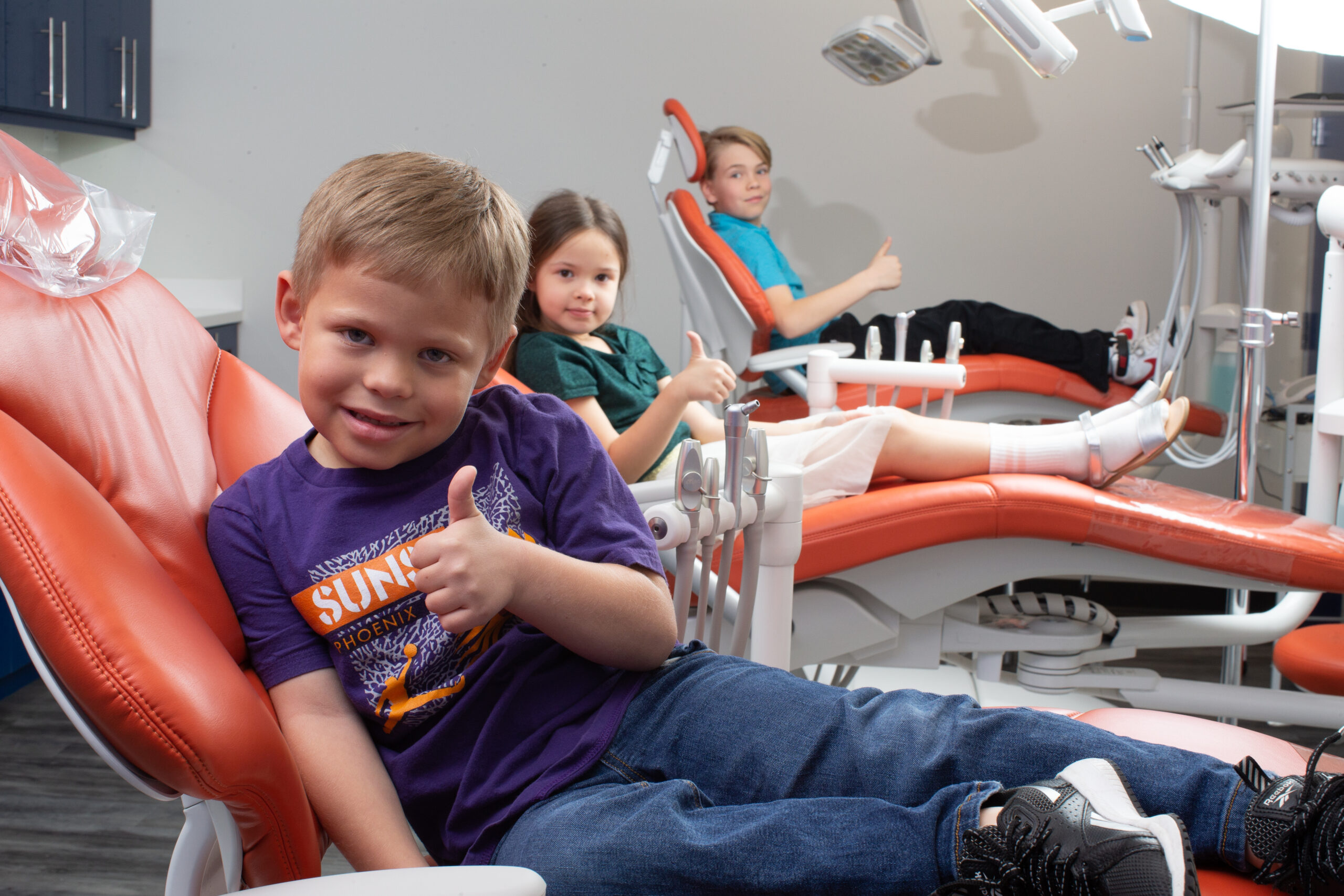 A group of children smiling happily while receiving care at Pediatric Dentists East Valley (PVPD)