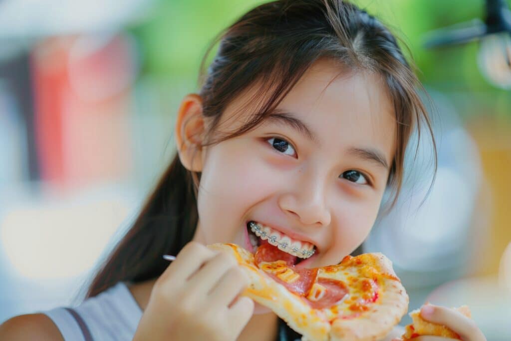 Child Wearing Braces Eating a Slice of Pizza